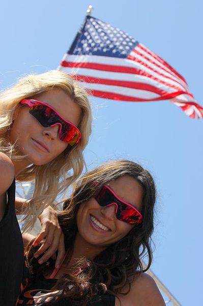 Women Wearing Oakley Sunglasses Under American Flag - Photo by Michael Dorausch